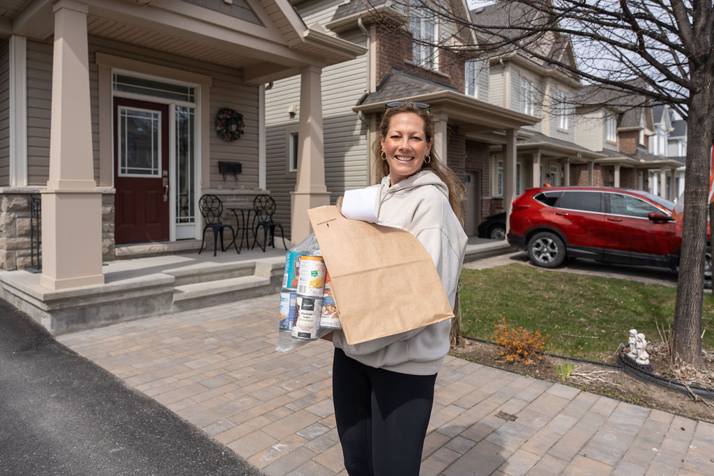 Volunteer carrying a bag and canned food collected during the Bridlewood Food Drive