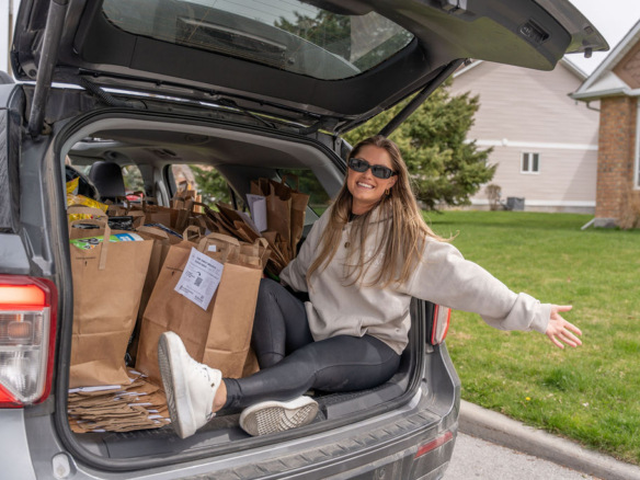 The West Team member sitting beside bags of donations collected during the Bridlewood Food Drive