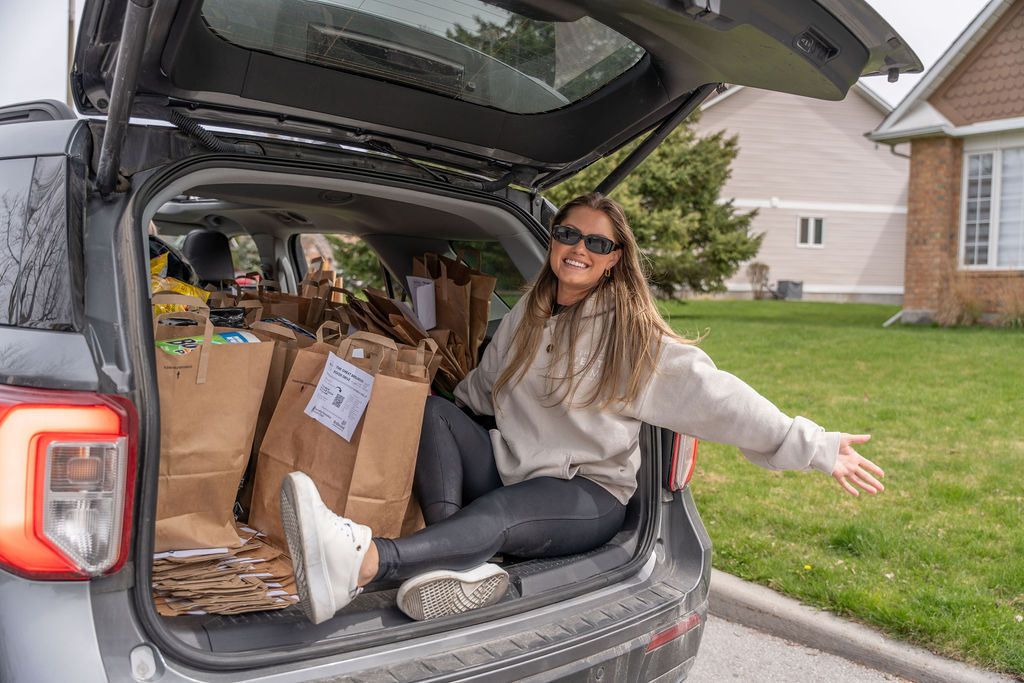 The West Team member sitting beside bags of donations collected during the Bridlewood Food Drive