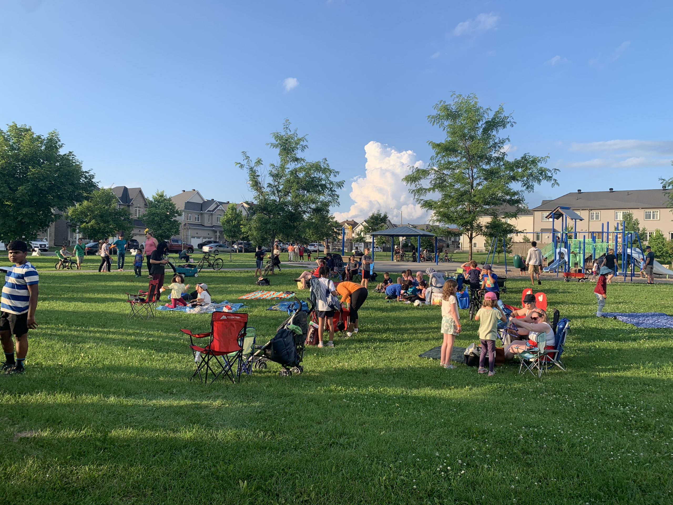 Families gathering on the lawn at Crownridge Park for The West Team’s Movie in the Park