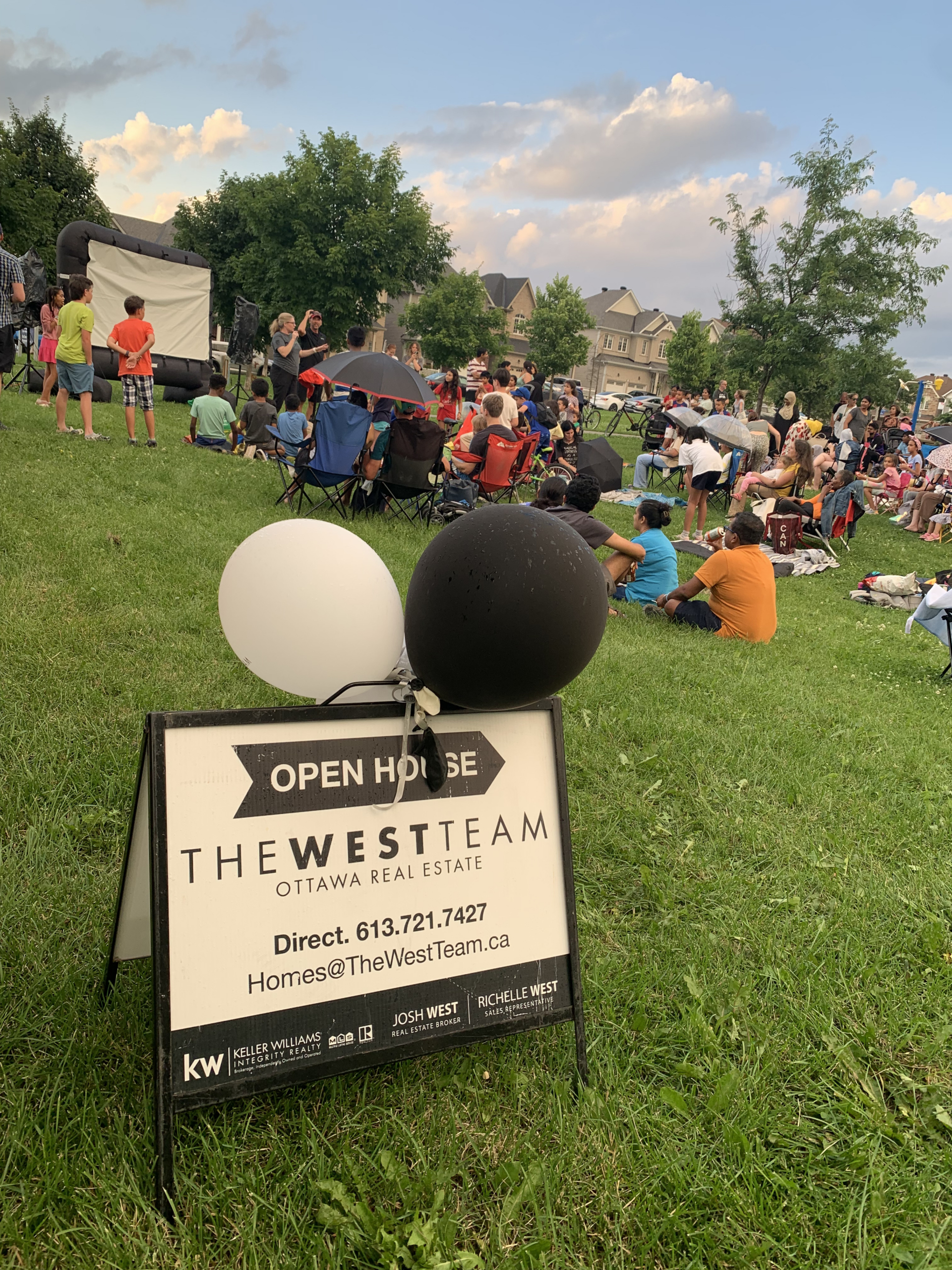 Families seated near an outdoor movie screen at The West Team’s Movie in the Park