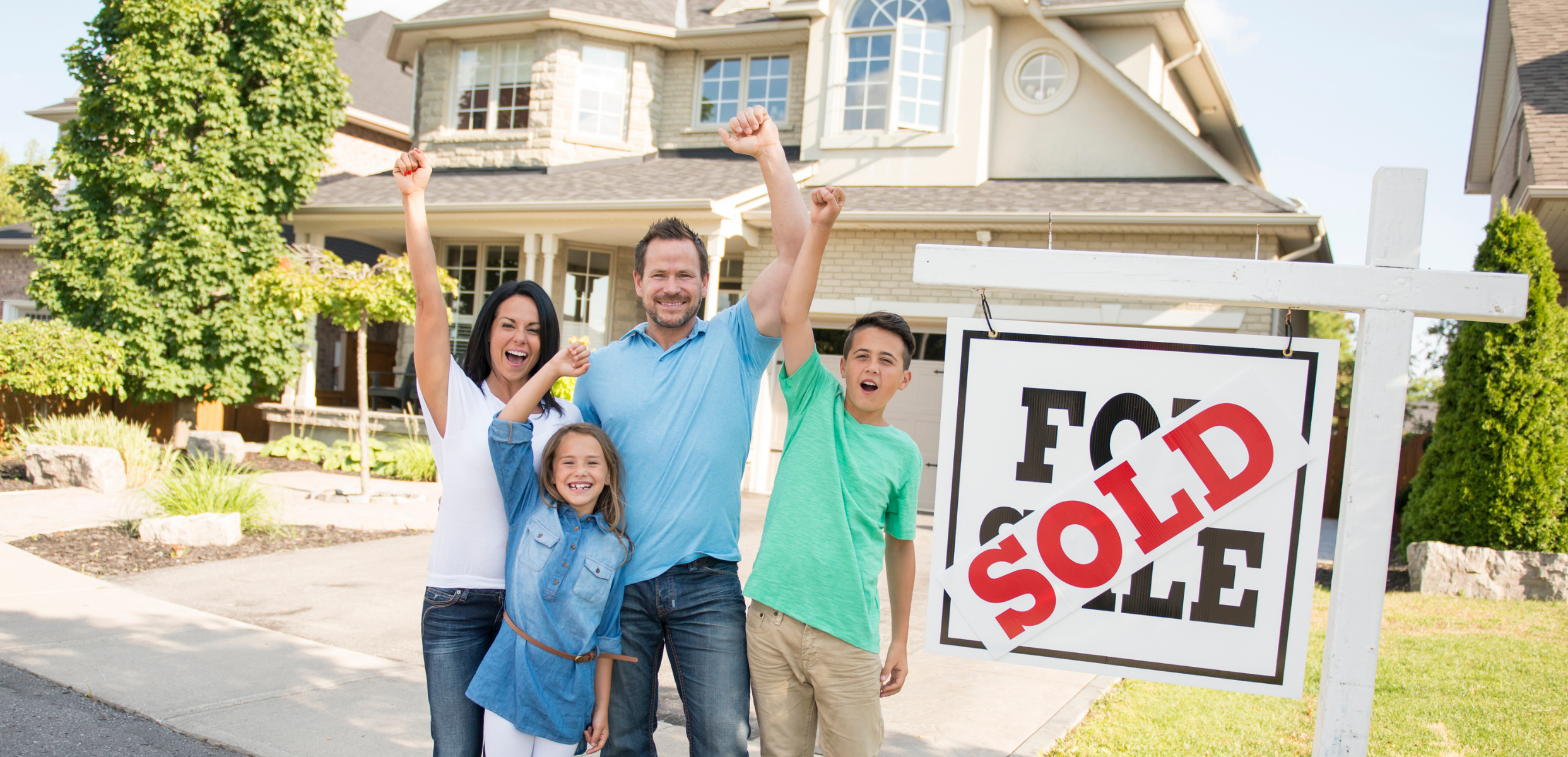 Family celebrating beside a sold sign in front of their new home
