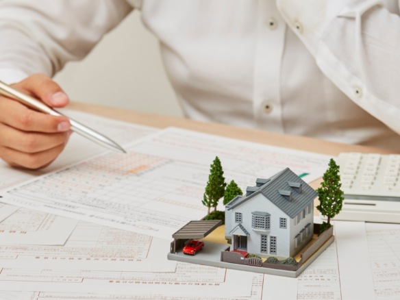 Model house beside a calculator and paperwork representing conditions in a home purchase offer