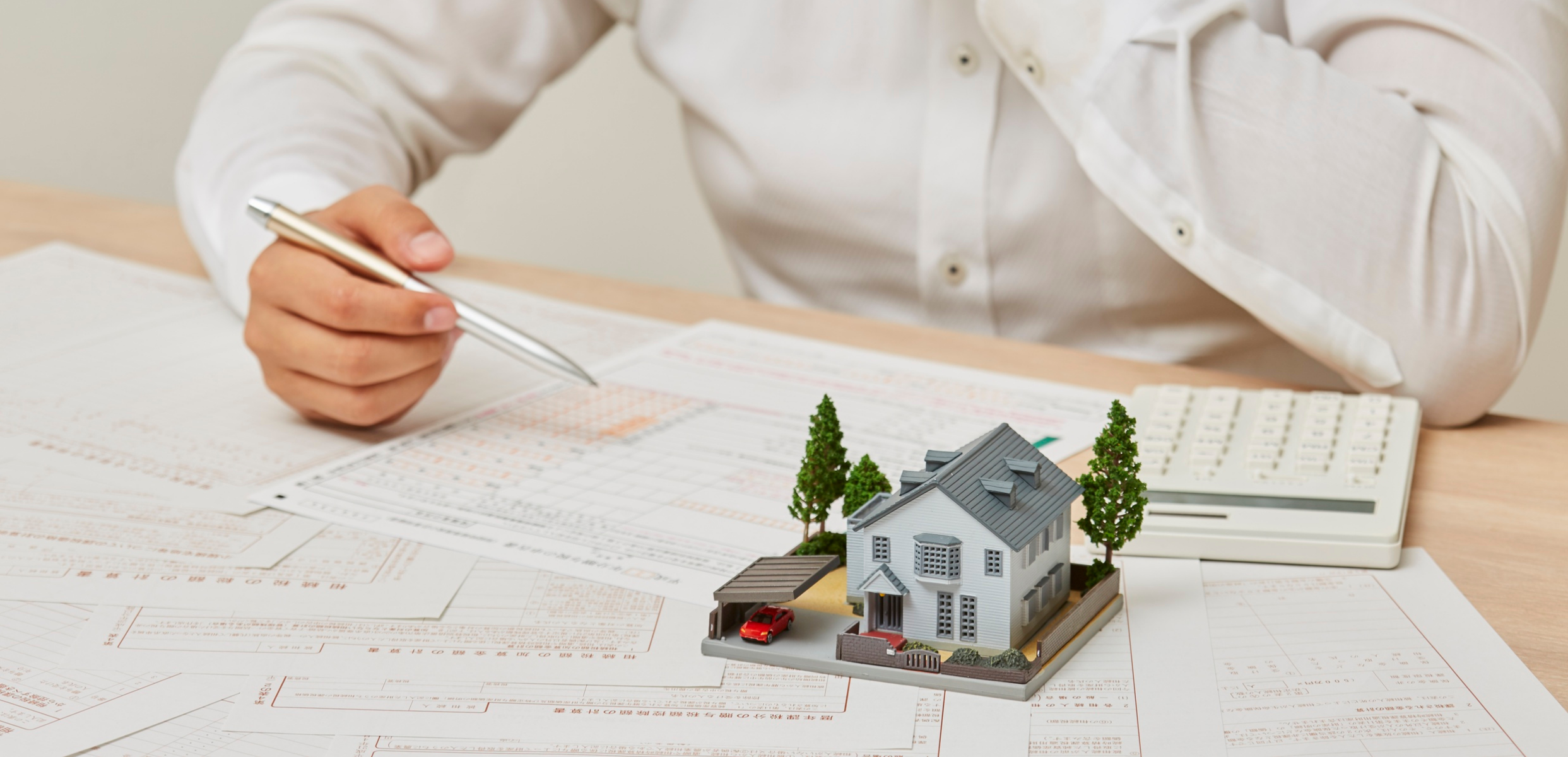 Model house beside a calculator and paperwork representing conditions in a home purchase offer