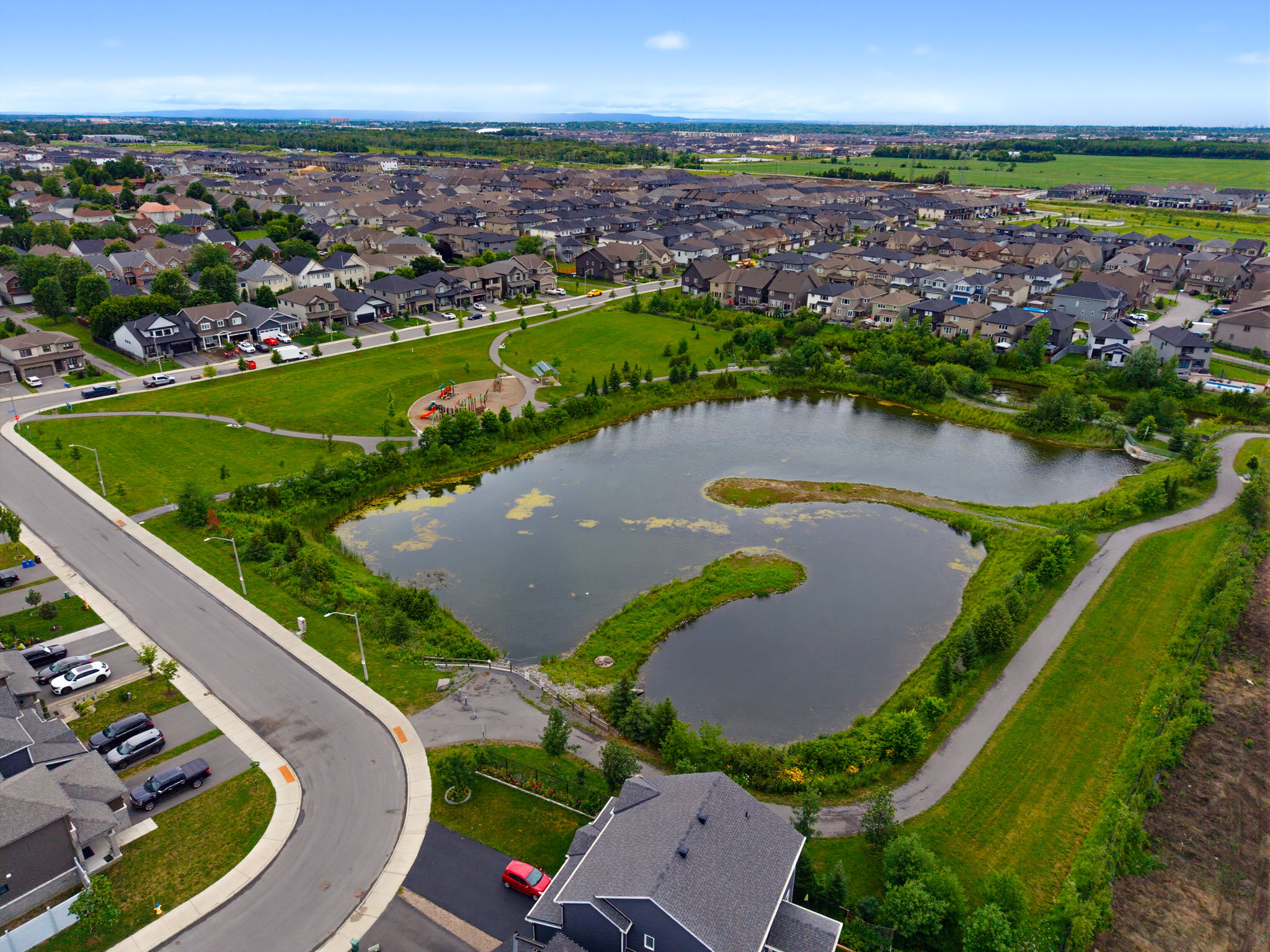 Aerial view of an Ottawa neighbourhood with homes, walking paths, a park and a pond- Sttitsville